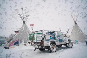 Photo of a tractor in the snow between two tepee dwellings